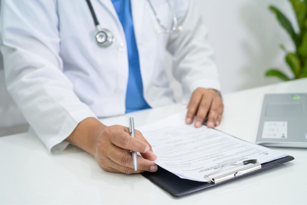 Doctor at desk with clipboard and laptop