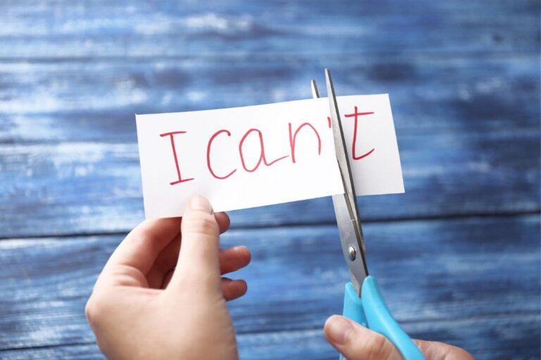 A hand with scissors cuts the word "can't" from a white paper, leaving "I can."
