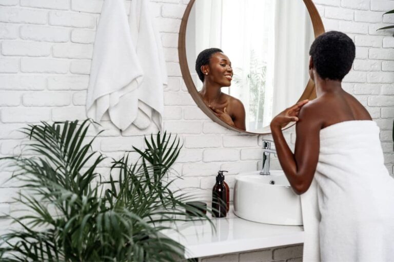 Woman with glowing skin looking in bathroom mirror