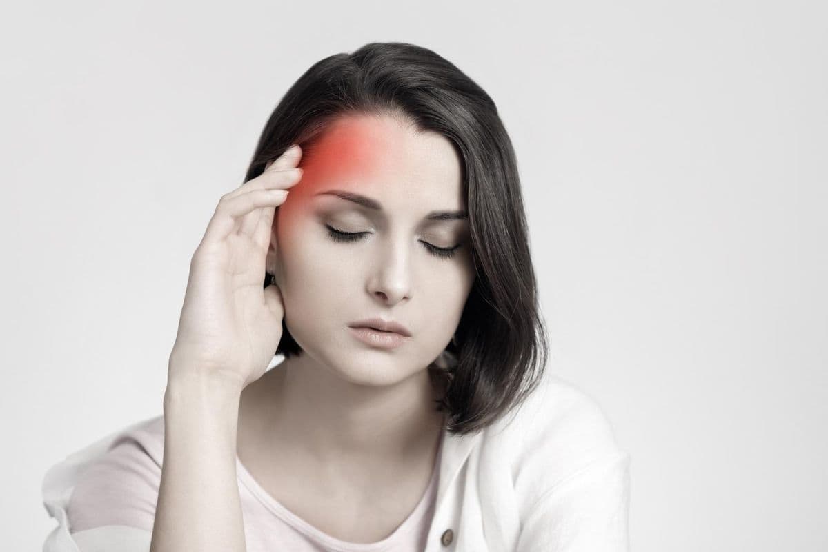 Woman with eyes closed and had on head, red on face indicates pain