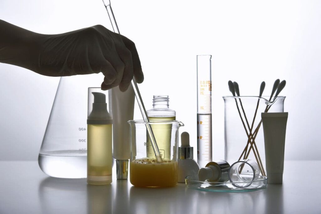 Gloved hand in laboratory stirring skincare chemicals