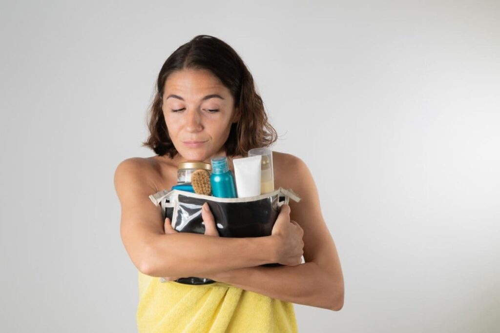 Woman holding cosmetics bag filled with creams and skincare products