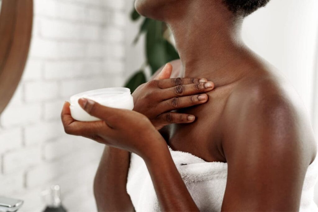 Woman applying lotion to her neck and chest