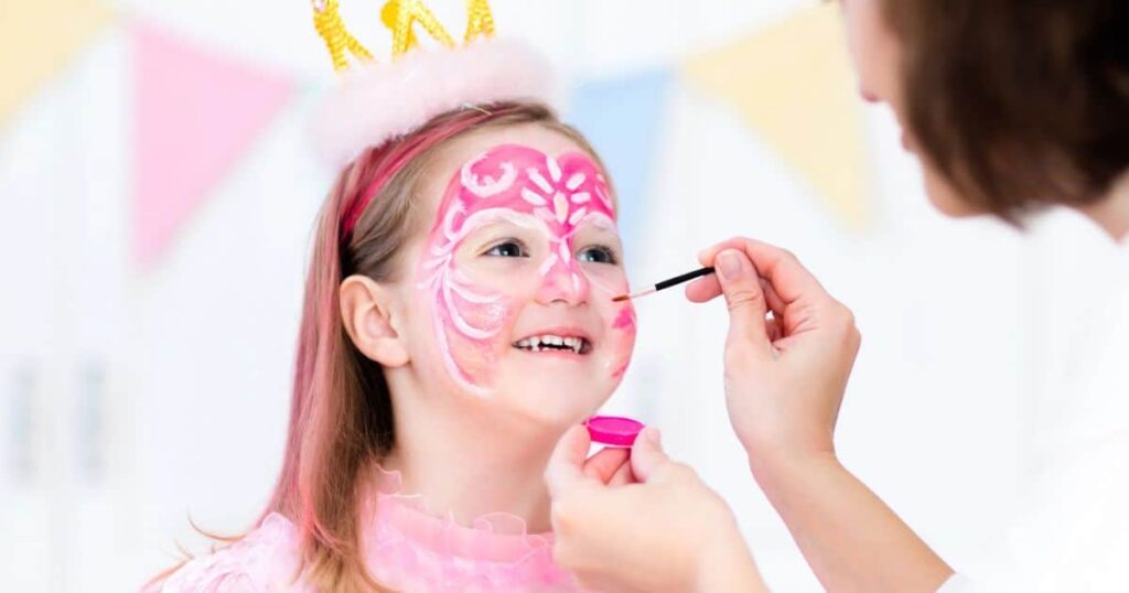 Mother applying Halloween makeup to daughter's face