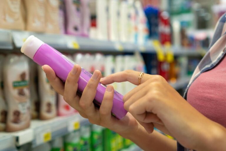 Woman decoding shampoo label at store.
