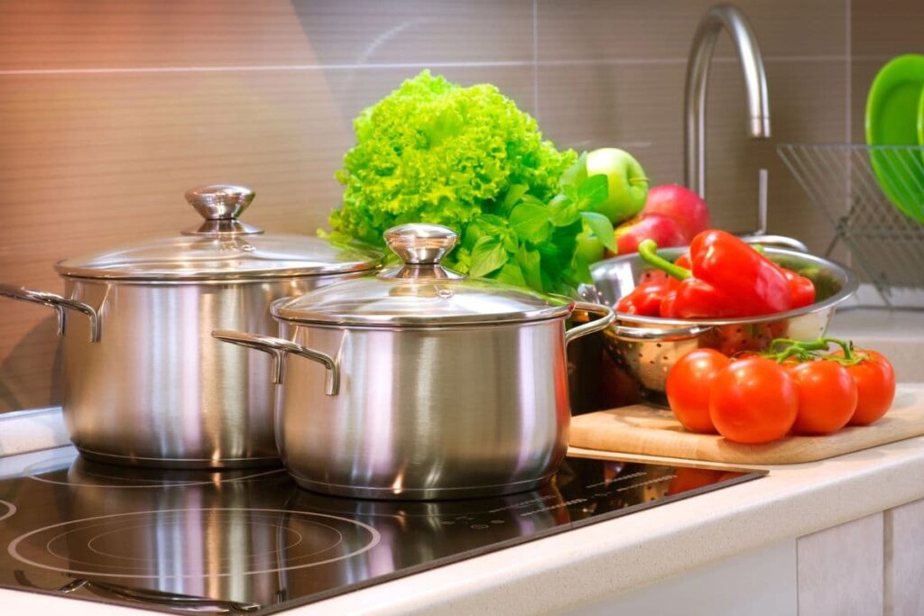 Stainless steel pots on cook top, tomatoes and lettuce nearby.