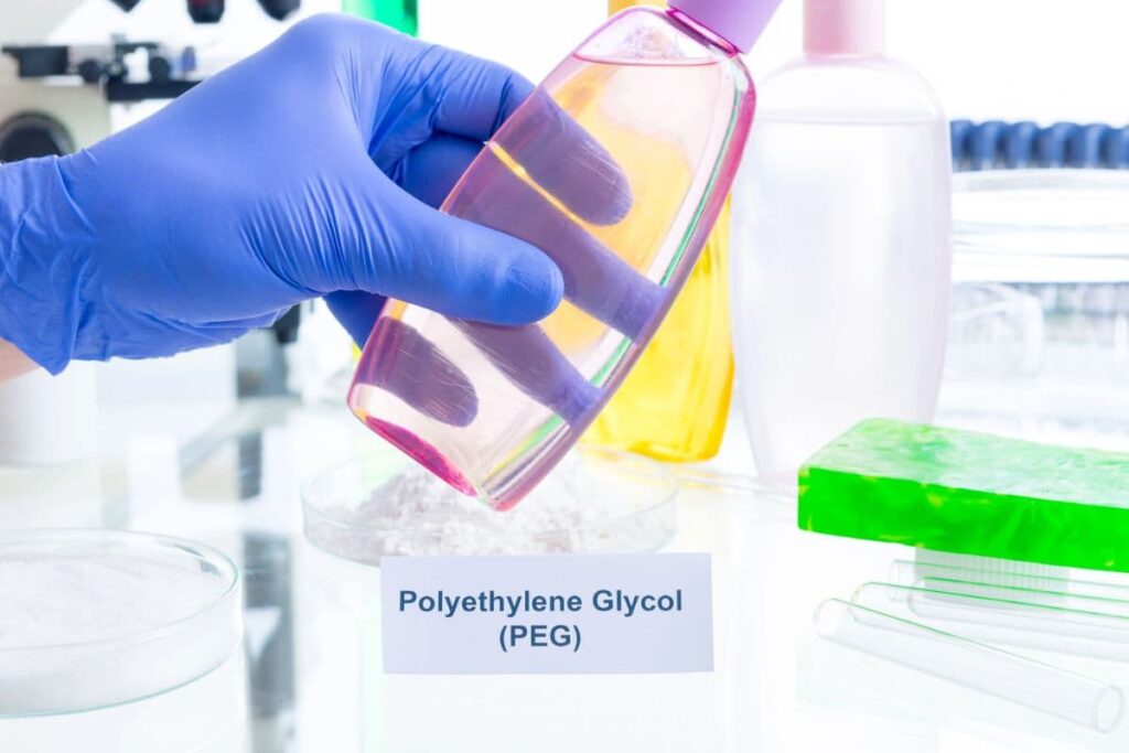 Gloved hand in laboratory holding bottle of baby shampoo with PEG chemicals labeled