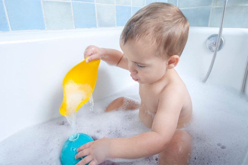 Baby boy playing with toys in bubble bath