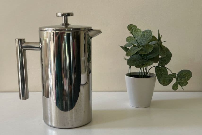 Non-toxic French press on table next to potted plant.