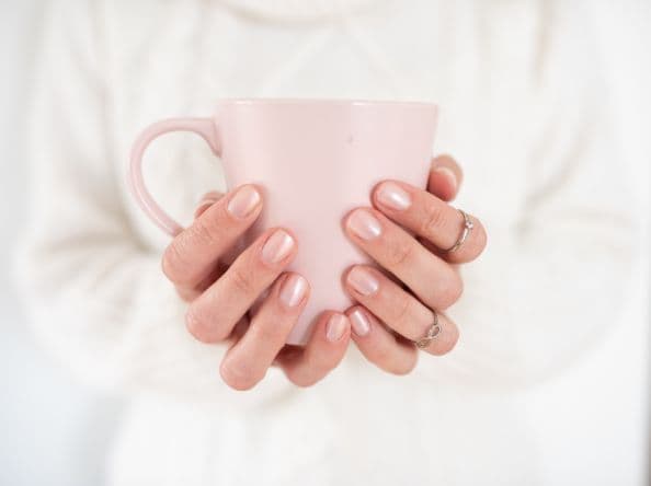 Woman's hands holding pink mug.