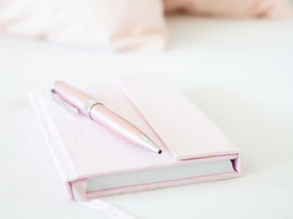 Pink journal and pen on countertop.