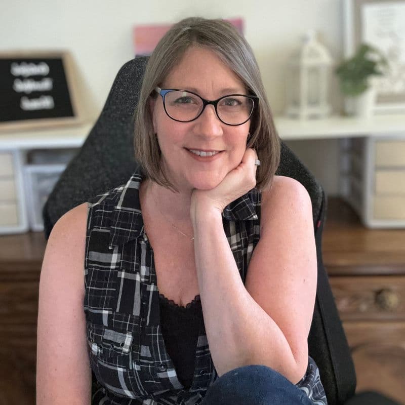 Tina Marie, author of Toxin-Free With Tina Marie, sitting in front of shelf with plant and diffuser.