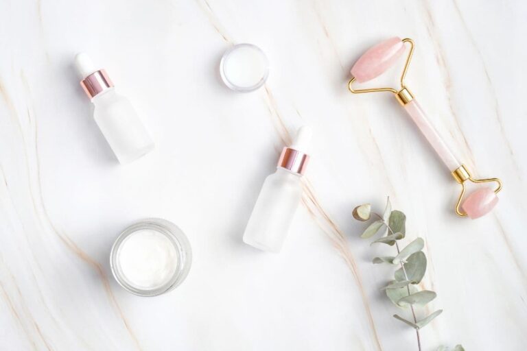 Jade roller and clean beauty products on quartz background