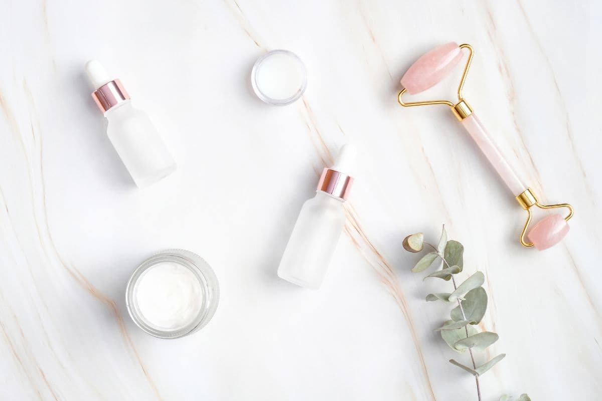 Jade roller and clean beauty products on quartz background