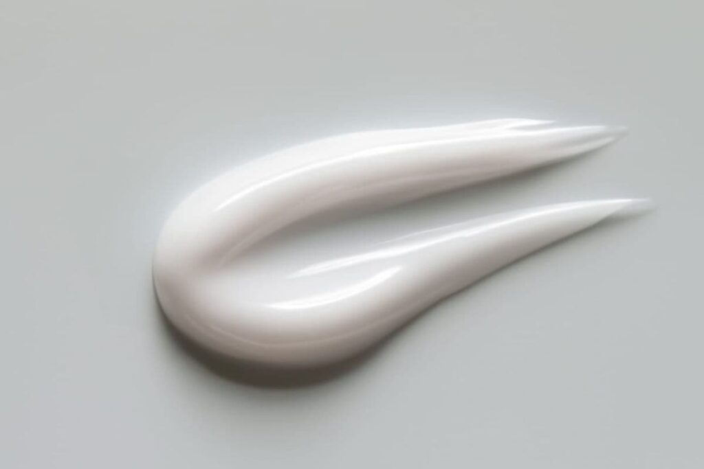 A swipe of retinol alternative lotion on white background.