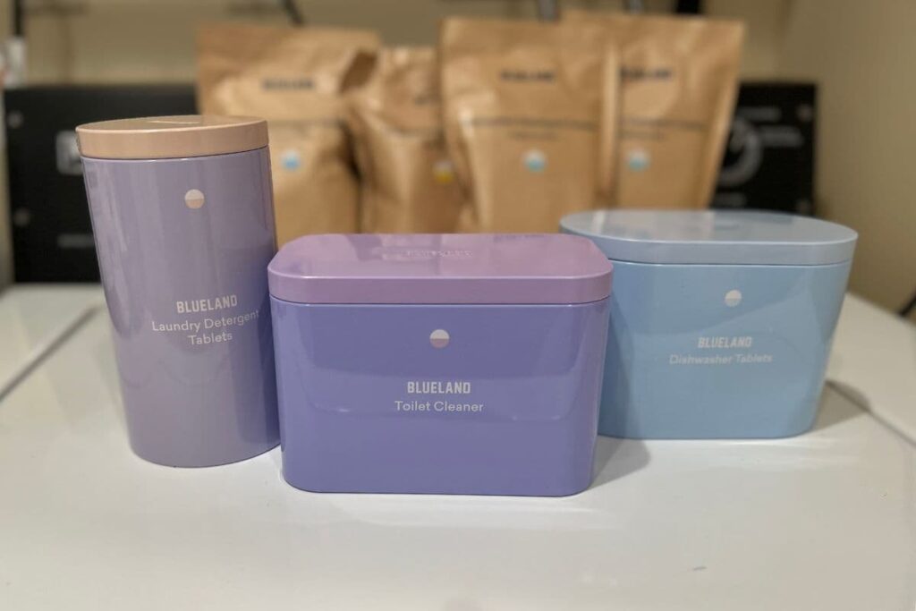 Blueland toilet cleaner, laundry tabs, and dishwasher tabs in tins and bags on my washing machine.