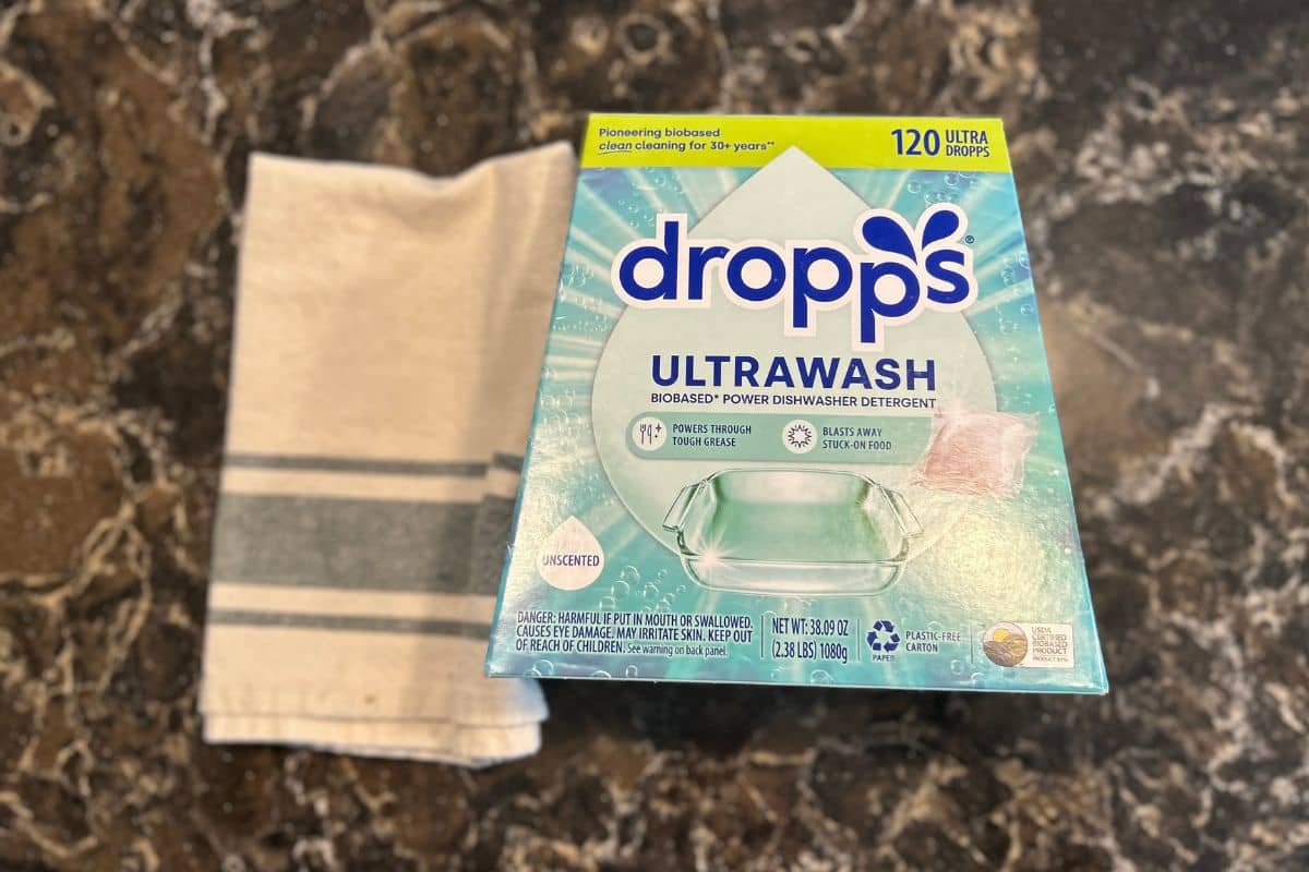 Box of Dropps Ultrawash dishwasher tabs next to dish towel on my counter.