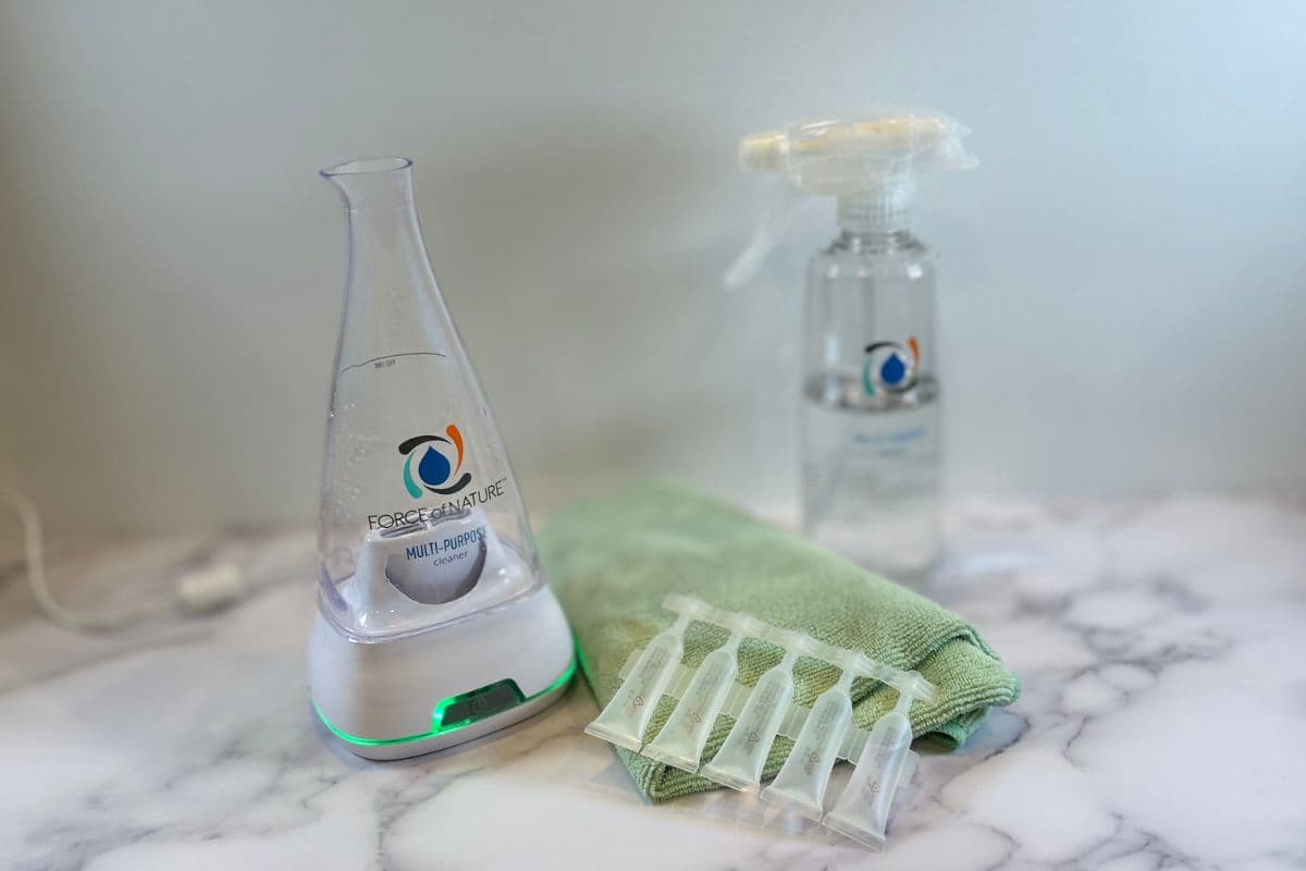 Force of Nature non-toxic cleaning system and solution capsules displayed on counter near a green towel.