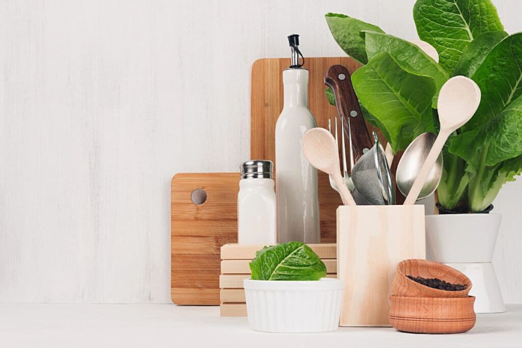 Wood cutting boards and utensils, ceramic bowl, greenery on counter.