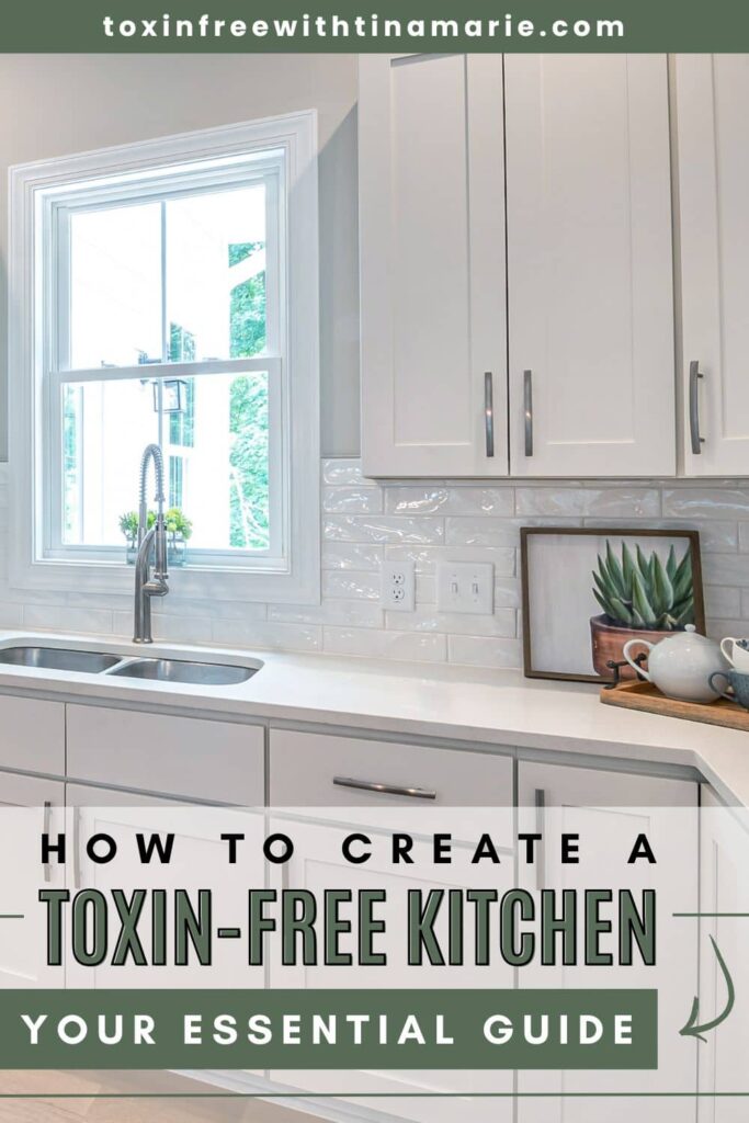 Bright kitchen with white cabinets, a sink below a window, and a framed succulent. Text reads "How to Create a Toxin-Free Kitchen: Your Essential Guide."