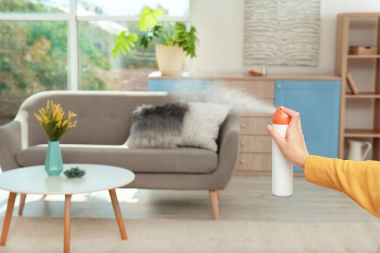 Woman spraying aerosol air freshener in living room