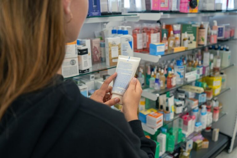 Woman holding a tube of cream while reading the label, representing awareness of side effects of retinol cream.
