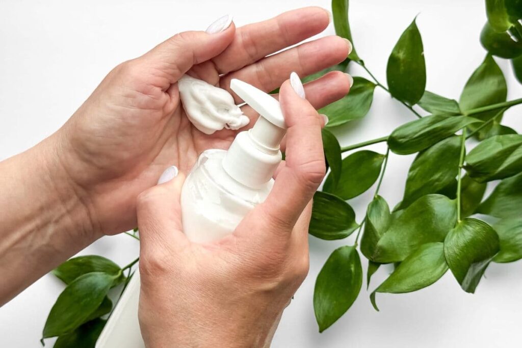 Woman dispensing lotion from bottle into palm of hand.