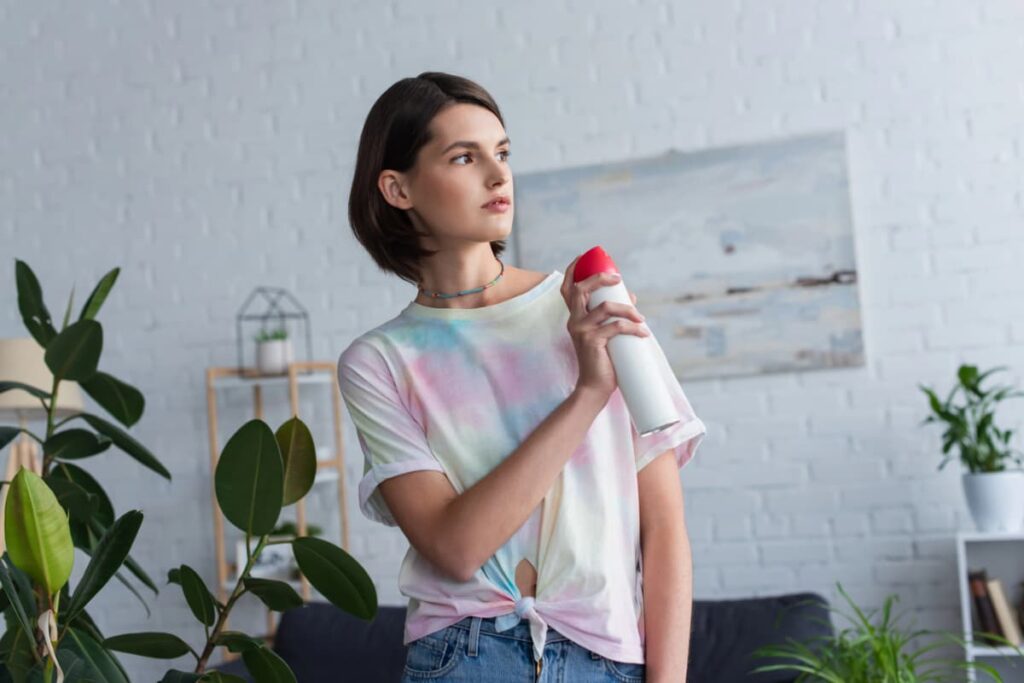 Woman holding an air freshener spray, an example of a product that can contribute to indoor air pollution.