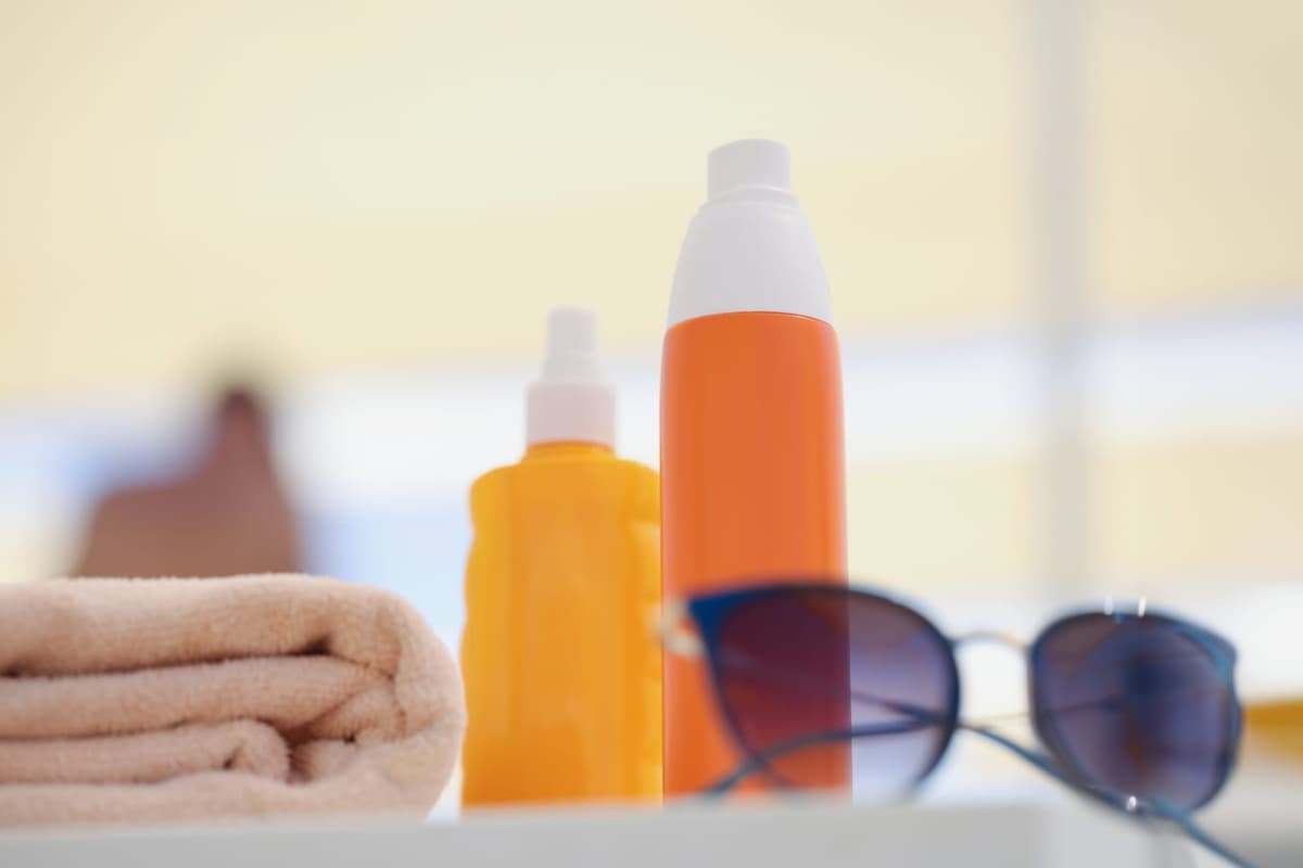 Sunglasses and towel with two bottles of mineral sunscreen