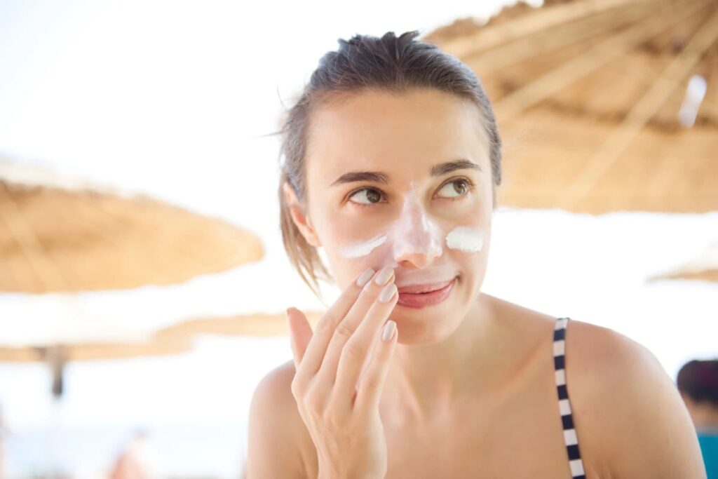 Woman applying safe mineral sunscreen for face.