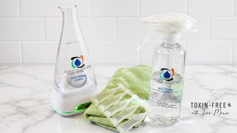 Force of Nature cleaner bottle, electrolyzer, tabs, and green cloth on counter.