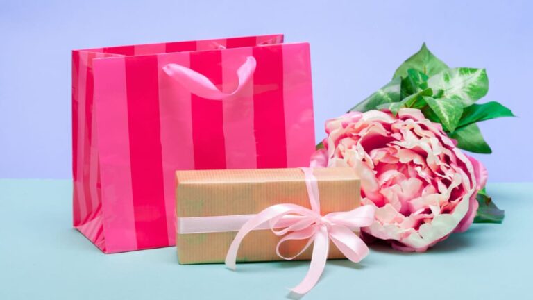 Non-toxic gifts for women, gift bag, gift box with bow, and peony on table.